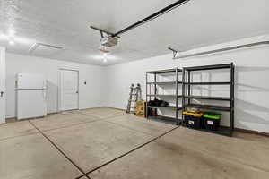 Garage with freestanding refrigerator and a garage door opener