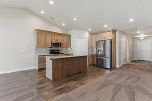 Kitchen with stainless steel appliances, decorative backsplash, wood finish floors, an island with sink, and recessed lighting