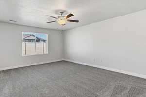 Spare room with dark carpet, a textured ceiling, and ceiling fan