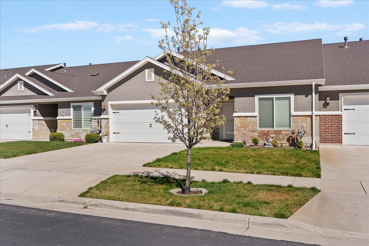 Craftsman inspired home with stone siding, concrete driveway, a front yard, stucco siding, and an attached garage