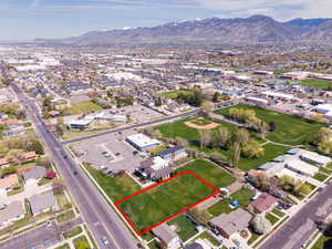 Aerial perspective of suburban area with property parcel outlined and a mountainous background