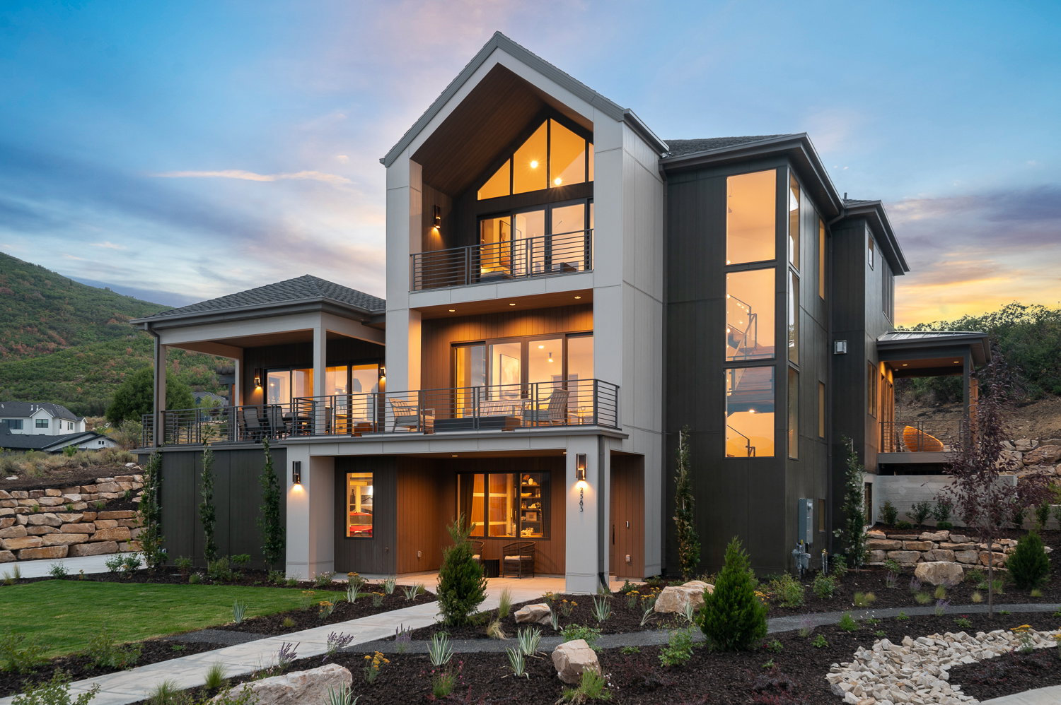 Back of property at dusk featuring a balcony, a lawn, a mountain view, and a patio area
