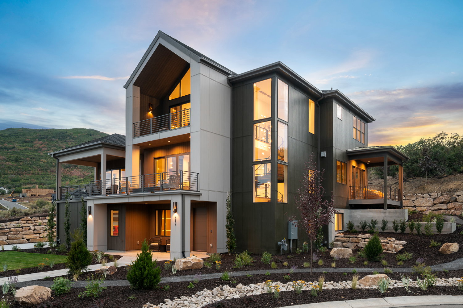 Back of property at dusk with a balcony and a patio area