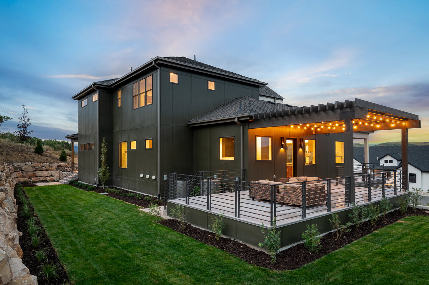 Back of house at dusk with a lawn, board and batten siding, a deck, and a pergola