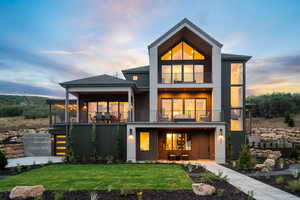 Back of property featuring a balcony, a yard, a shingled roof, and board and batten siding
