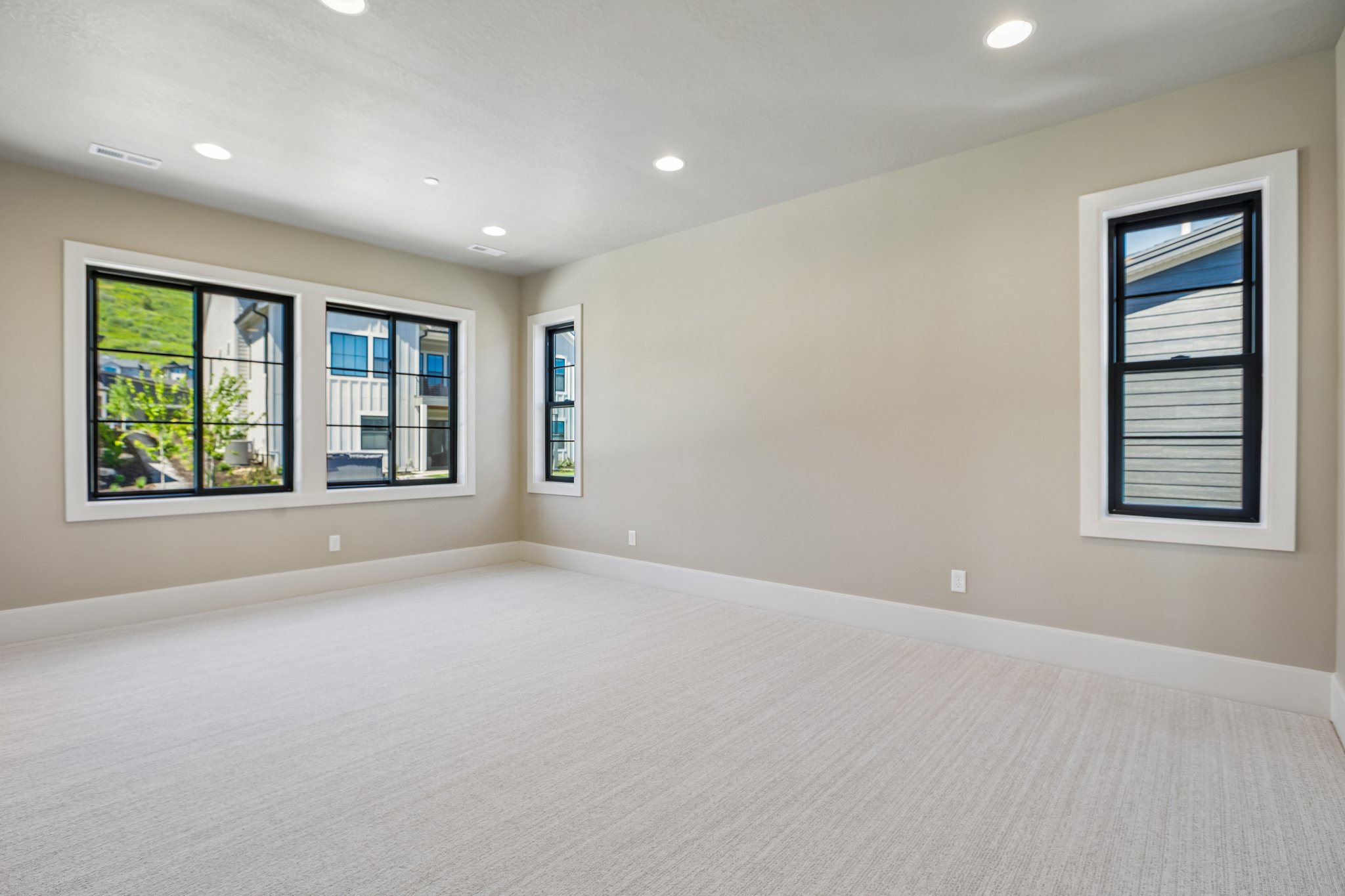 Spacious room featuring light-colored carpeting, neutral wall paint, and white trim