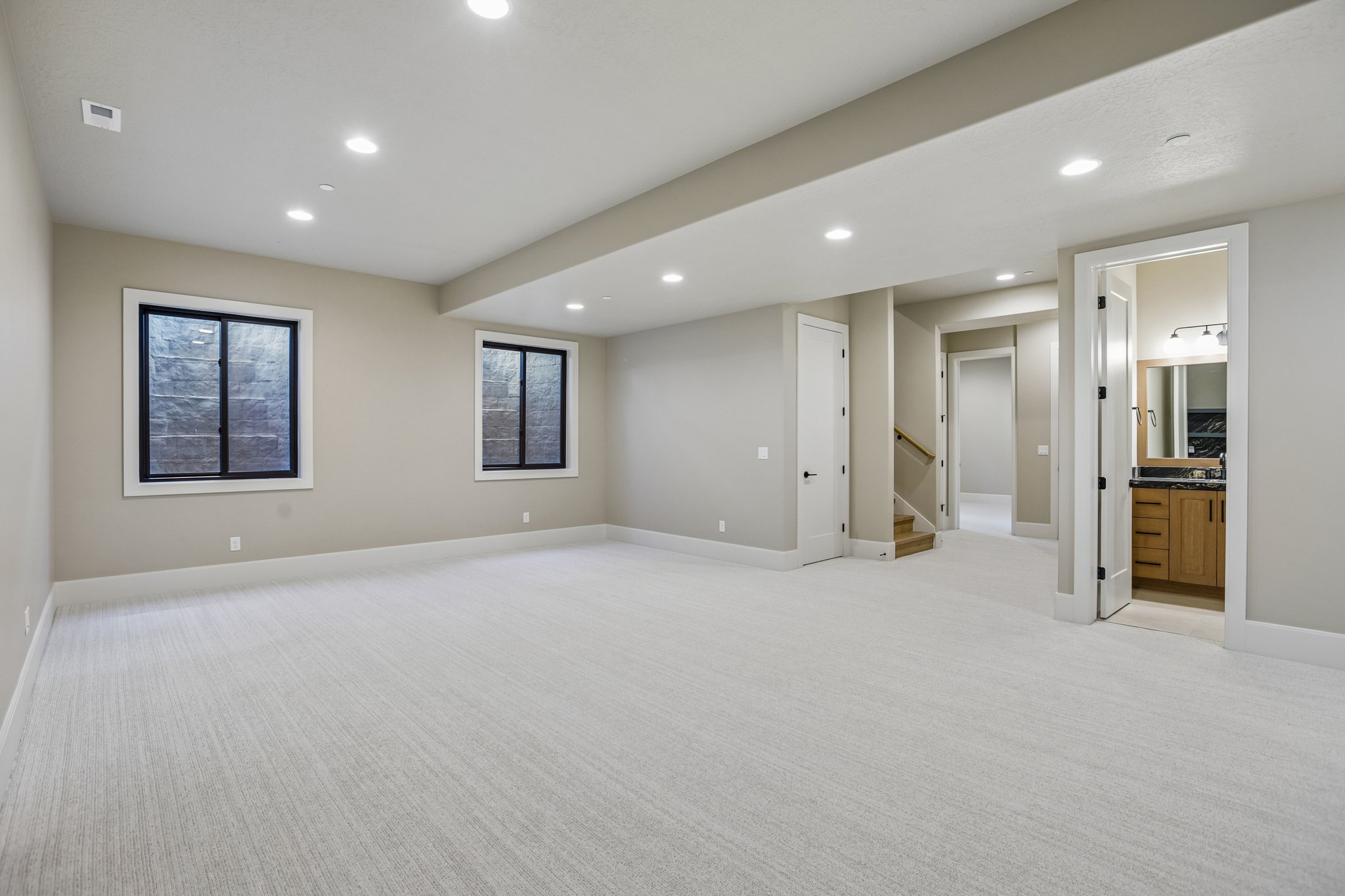 Spacious room with light-toned carpet flooring, recessed lighting, and two windows