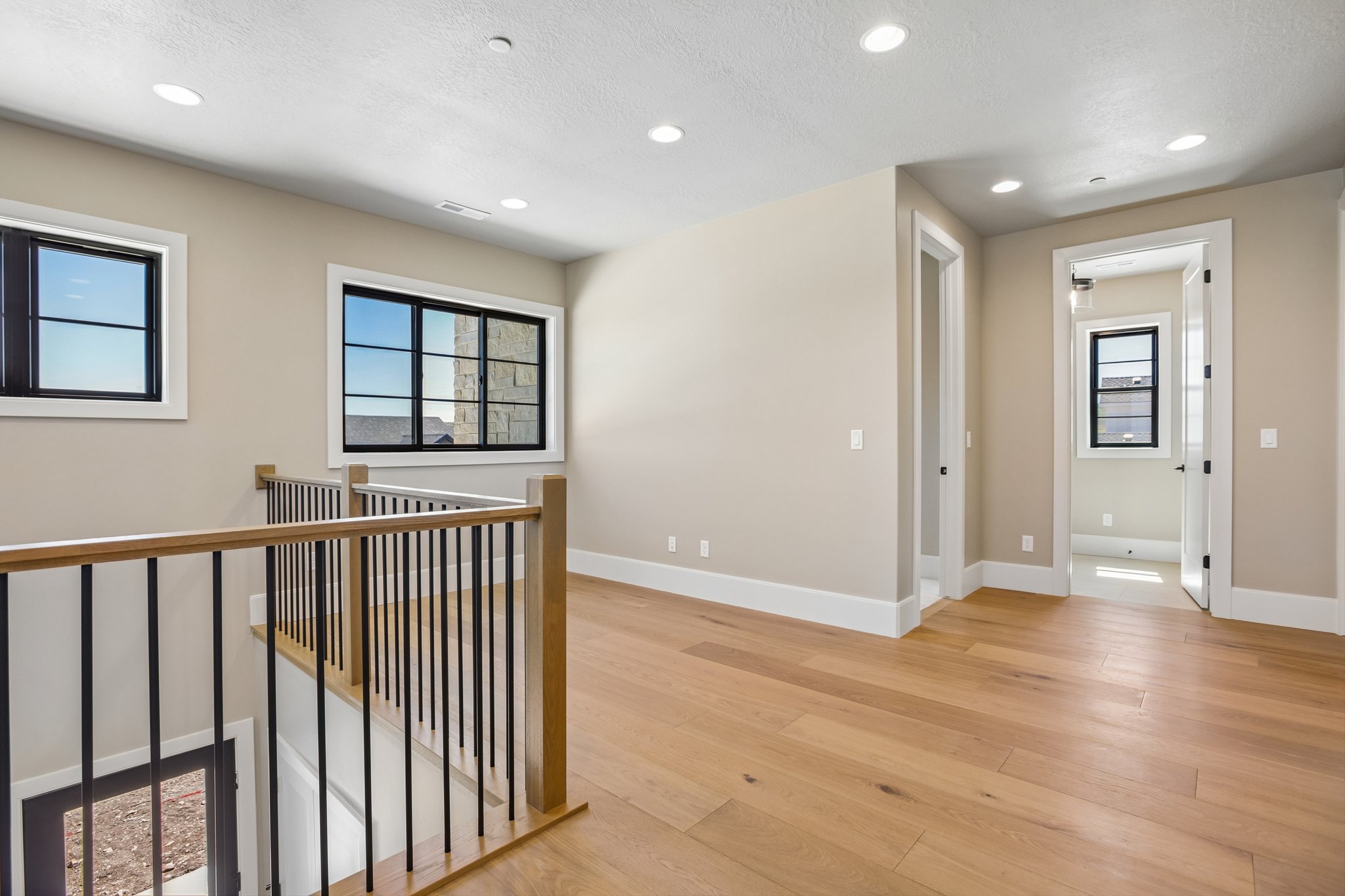 Spacious open landing featuring light wood-finish flooring and recessed lighting
