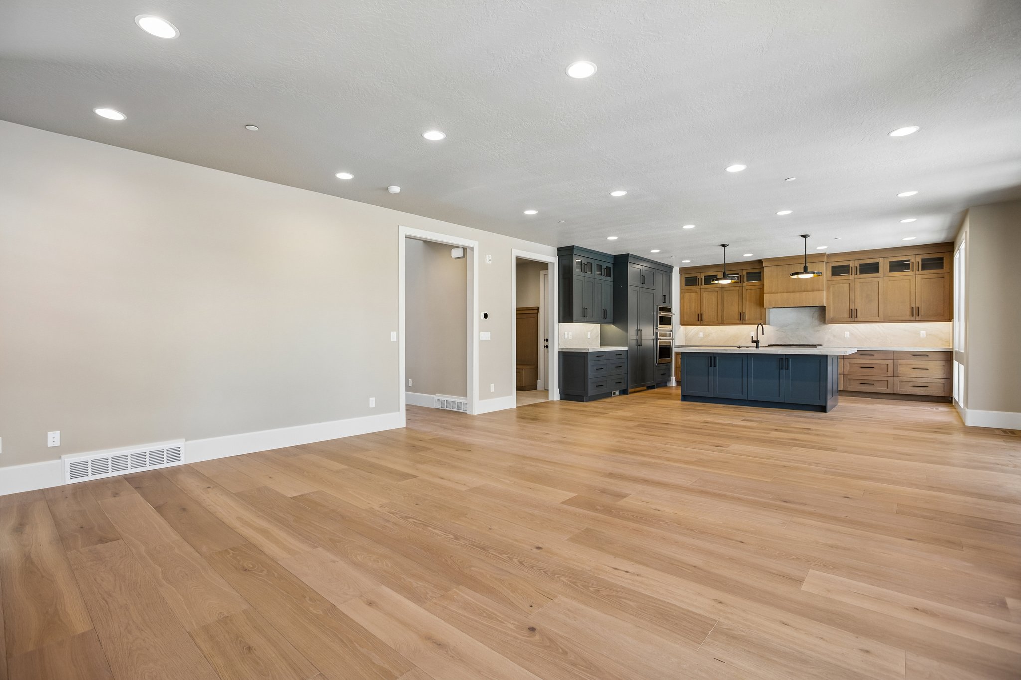 Open-concept living space with light wood-finish flooring extending into the kitchen