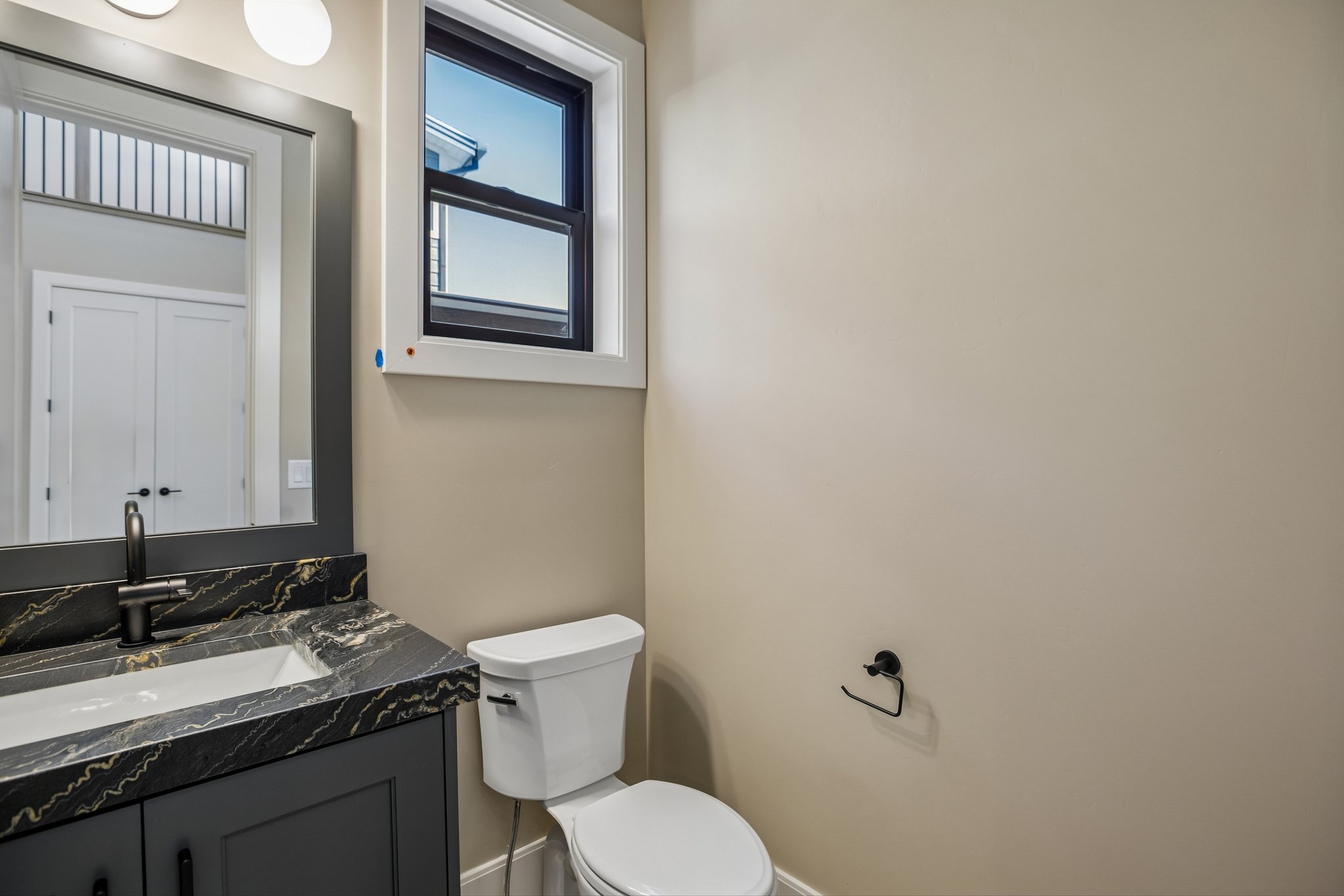 Bathroom featuring a dark vanity with a patterned countertop, an undermount sink, and a matte black faucet