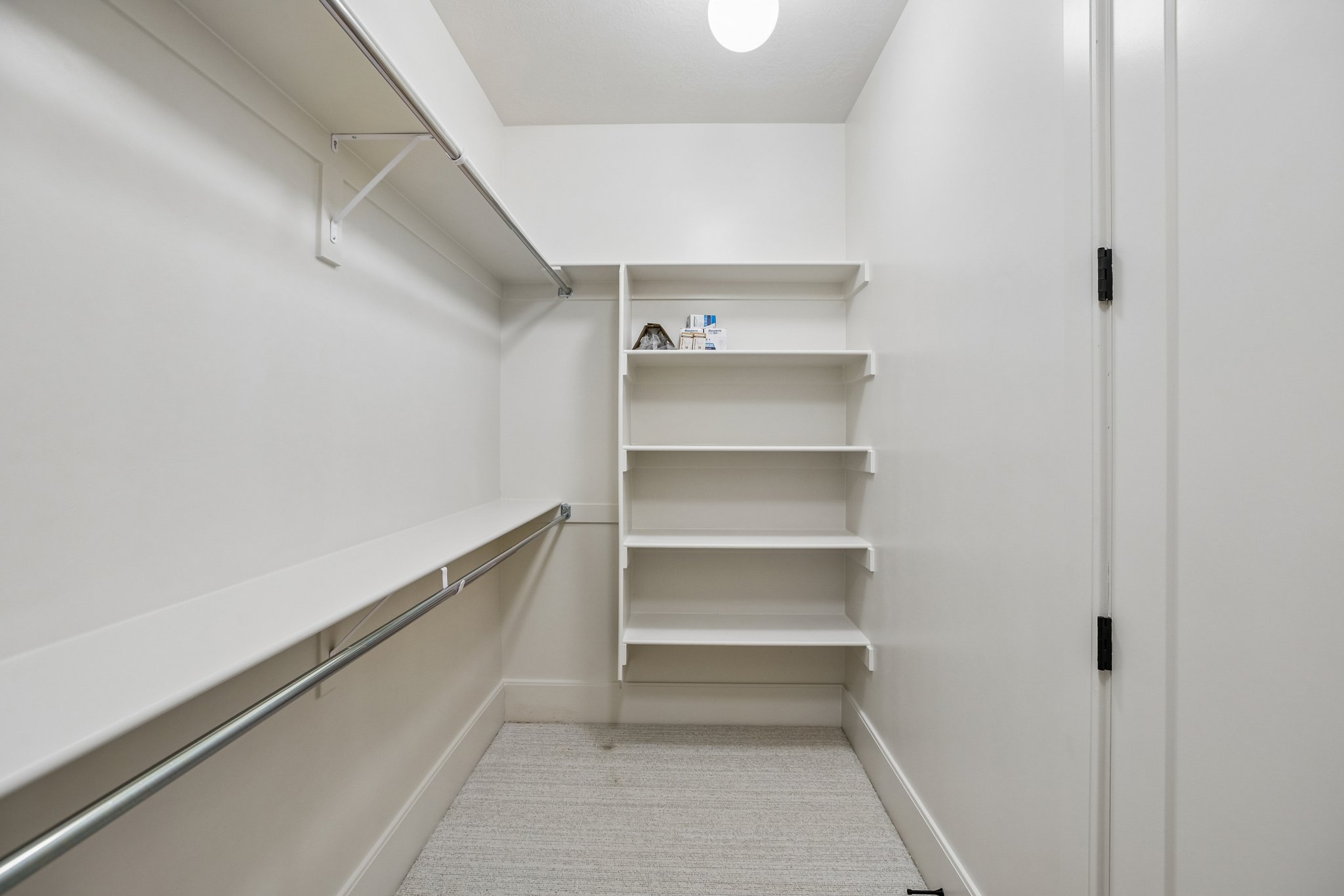 Walk-in closet featuring built-in shelving, chrome hanging rods, recessed lighting, and light-toned carpeting