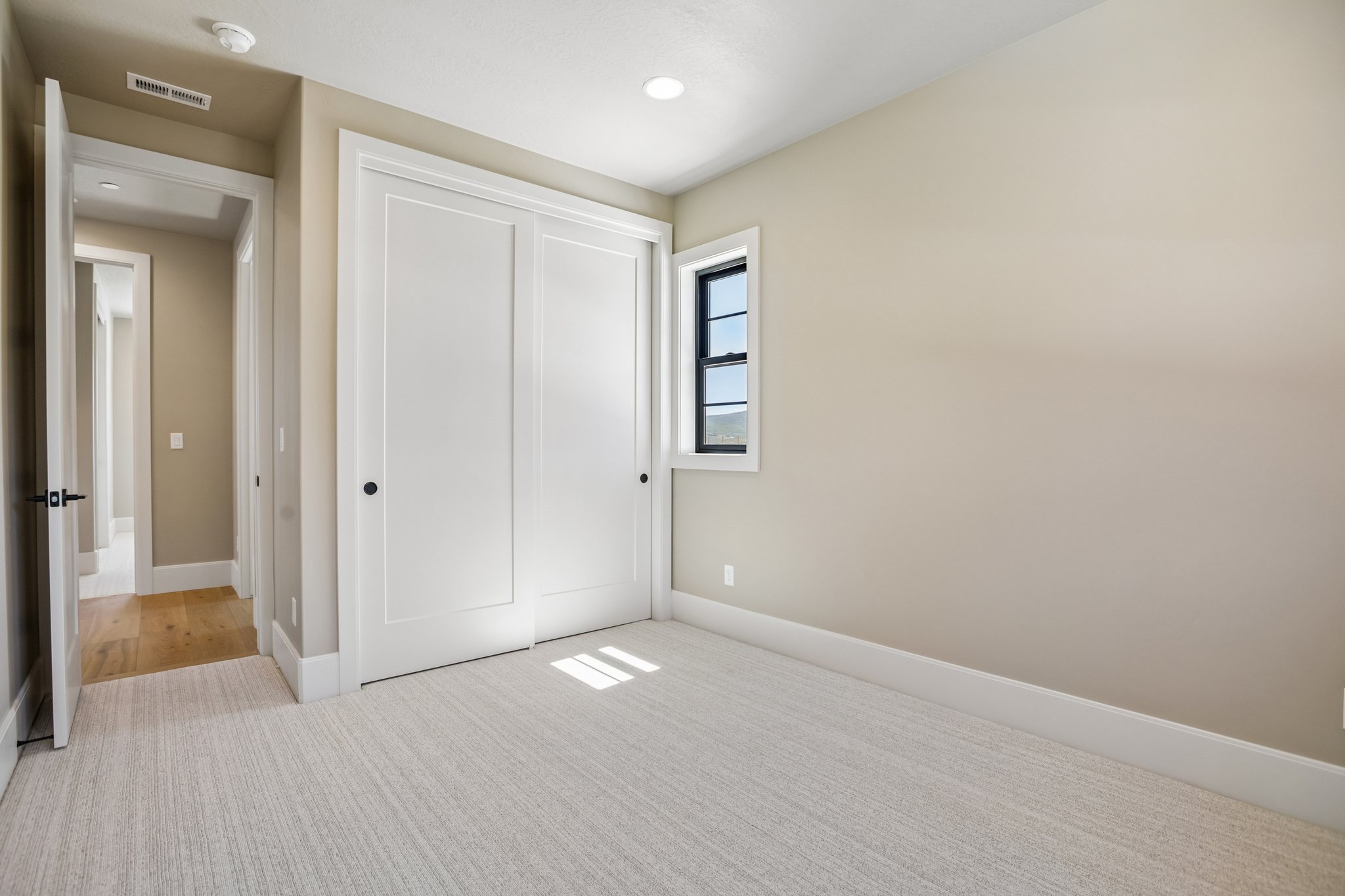 Carpeted room featuring a double-door closet, single pane window, and light neutral wall finishes
