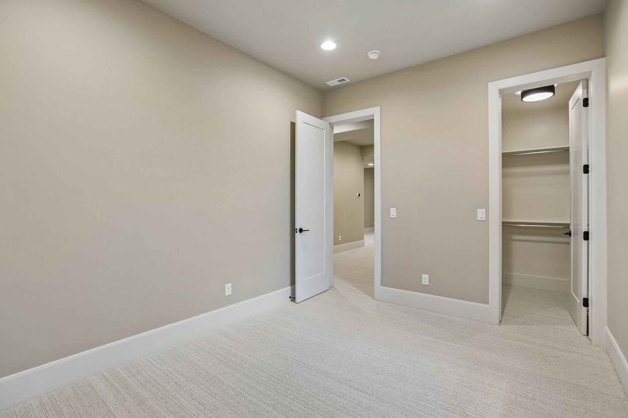 Neutral-toned room with plush carpet flooring, recessed ceiling lighting, and a closet featuring built-in shelving