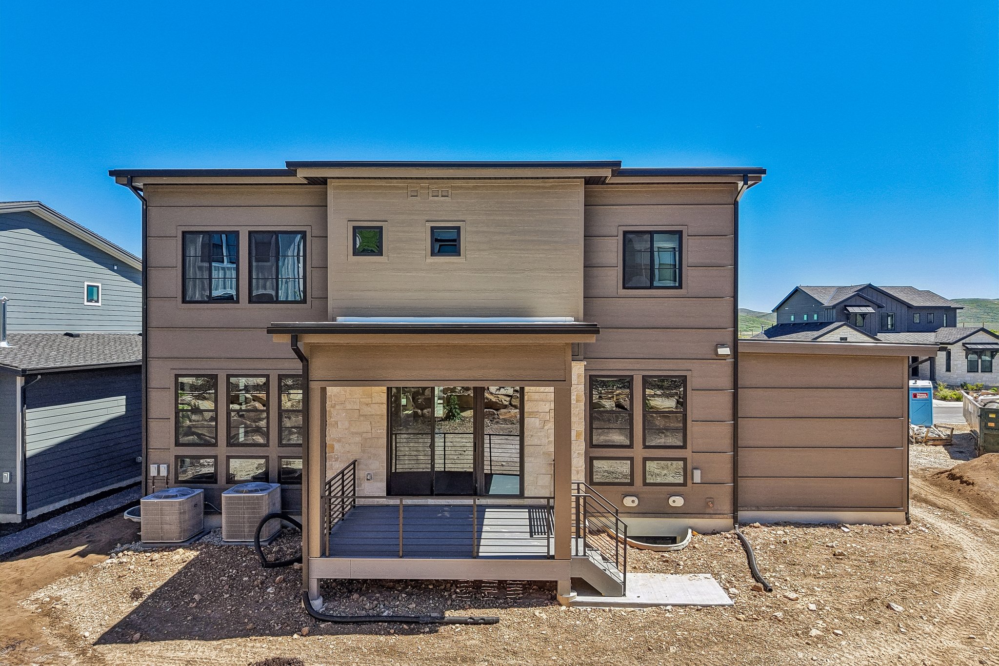 Contemporary multi-level exterior with a ground-level deck featuring dark railing