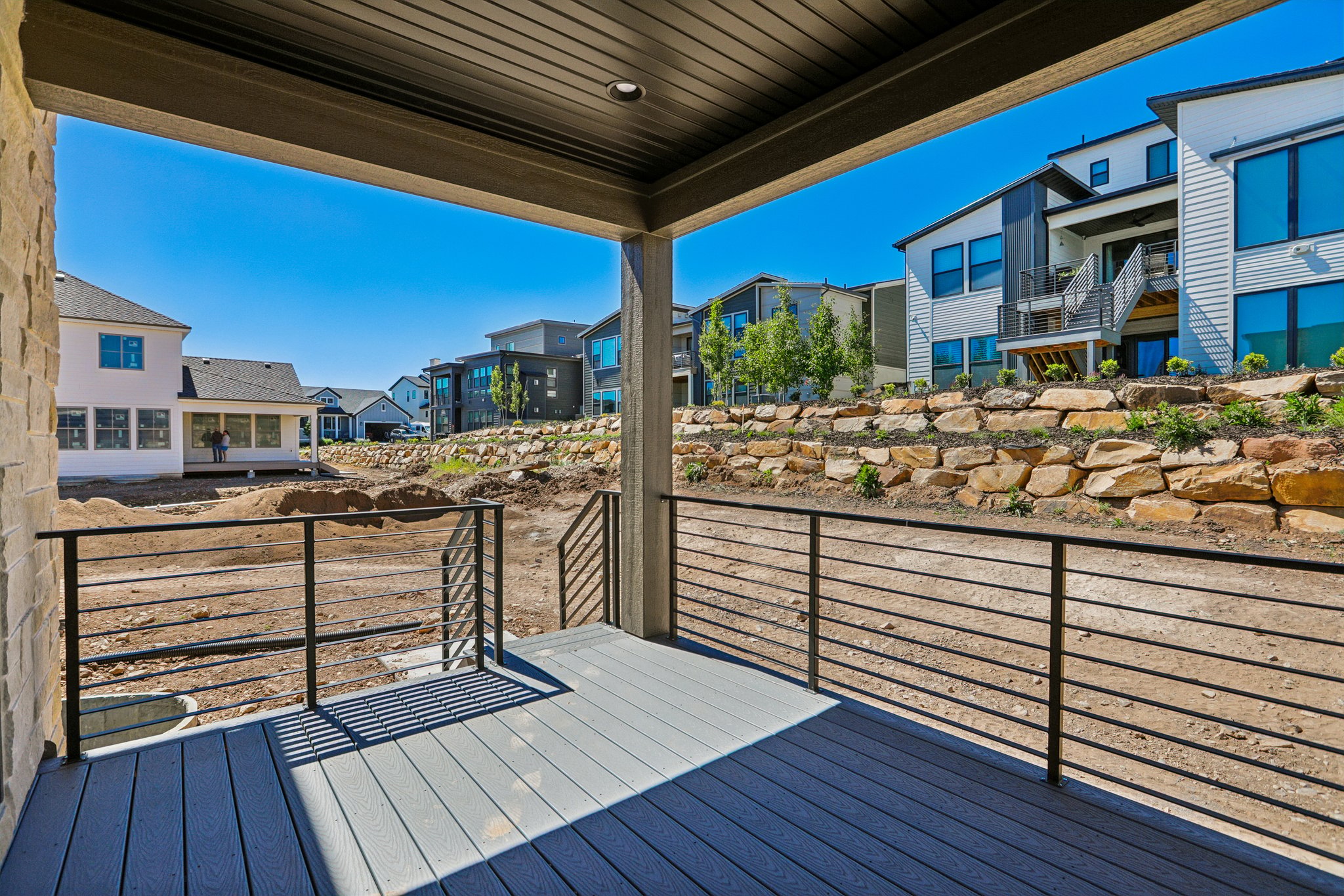 Covered outdoor deck with composite decking and black metal railings