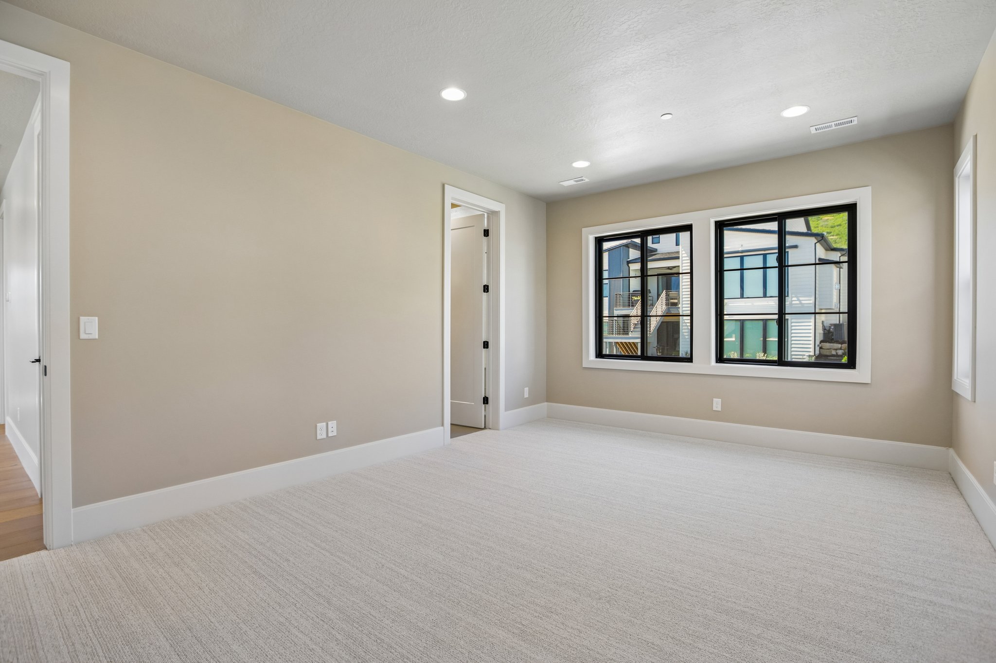 Spacious room featuring neutral wall tones, light-toned carpeting, and recessed lighting