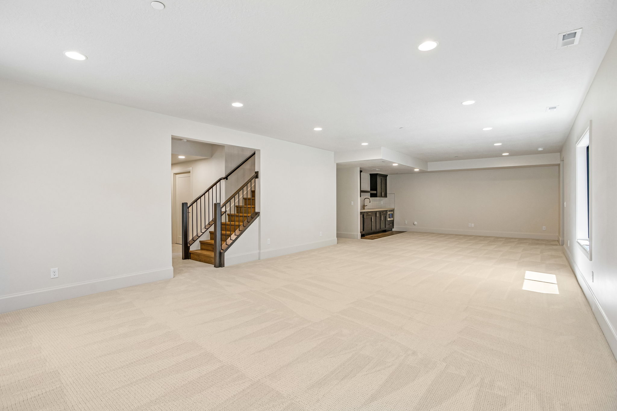 Expansive lower-level space featuring light-toned carpeting and recessed ceiling lighting