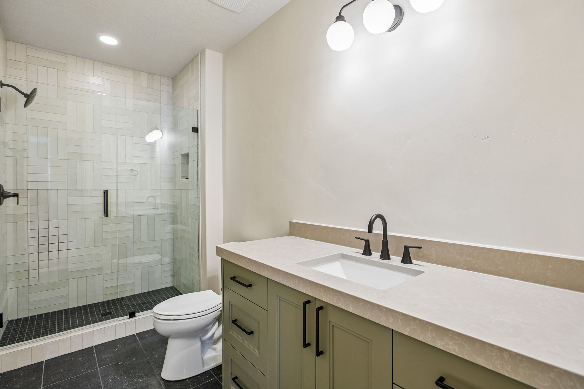 Bathroom featuring an enclosed shower with light-toned tiled walls and a dark tiled floor