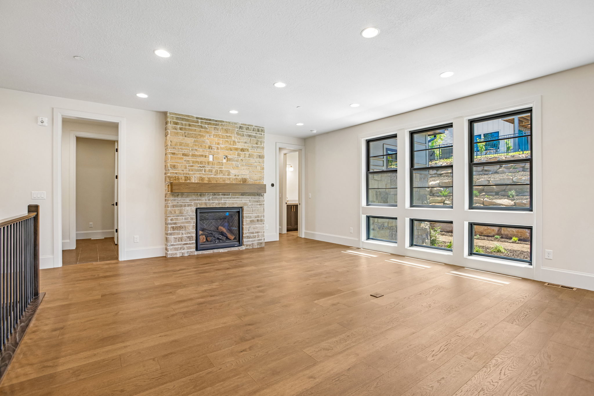Spacious interior featuring wood-finish flooring, recessed lighting, and a stone-clad fireplace with a wood mantel