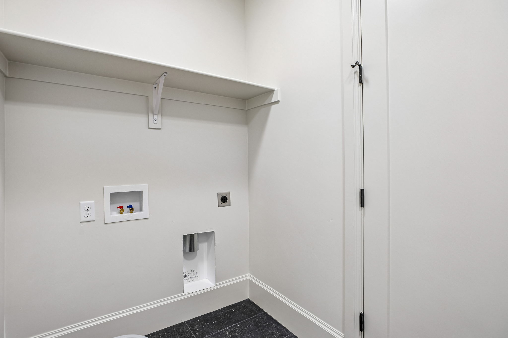 Dedicated laundry area featuring a utility shelf, electrical outlets, and plumbing hookups