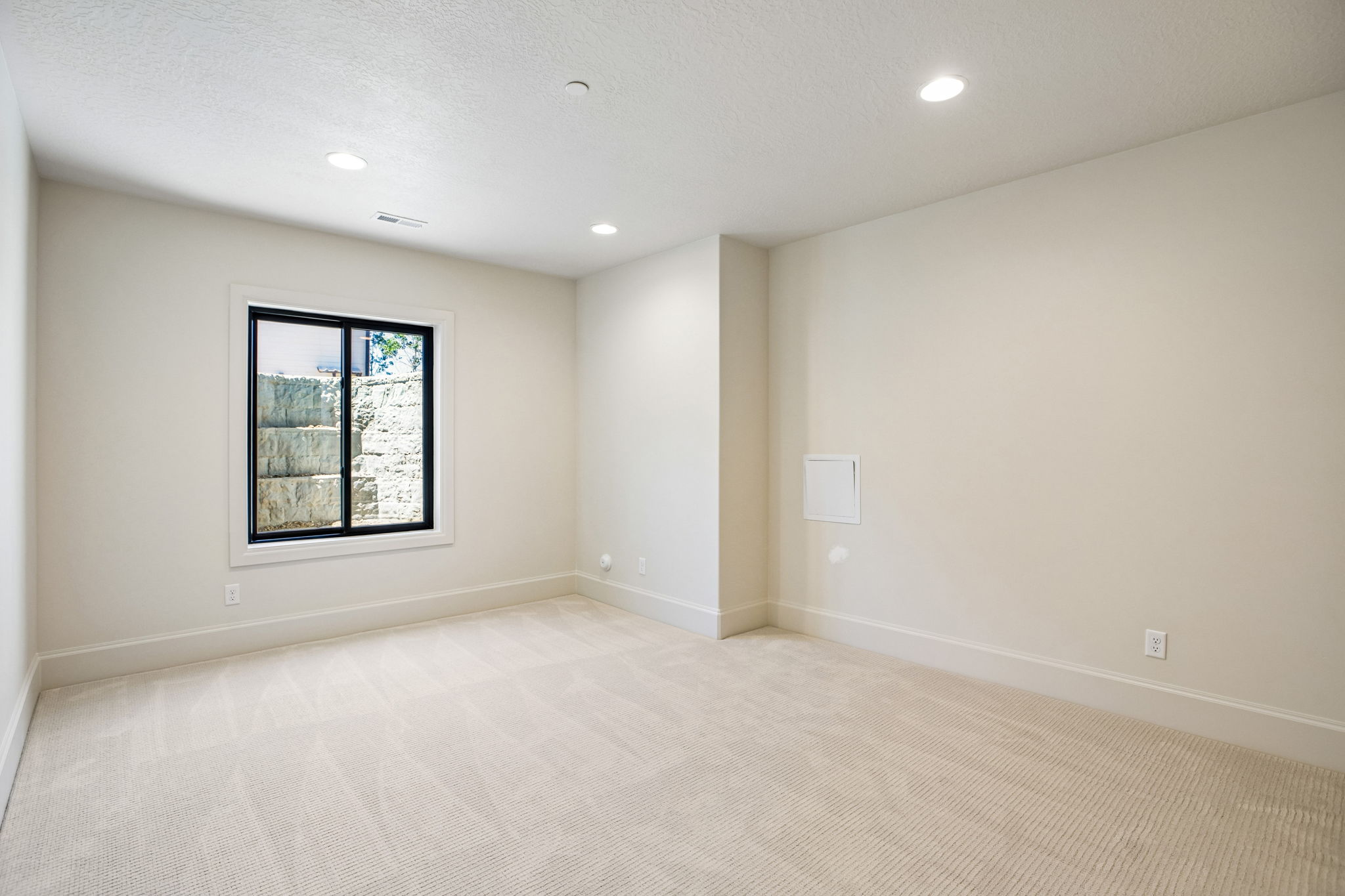 Carpeted room featuring a single window with a black frame, recessed lighting, and light-toned walls