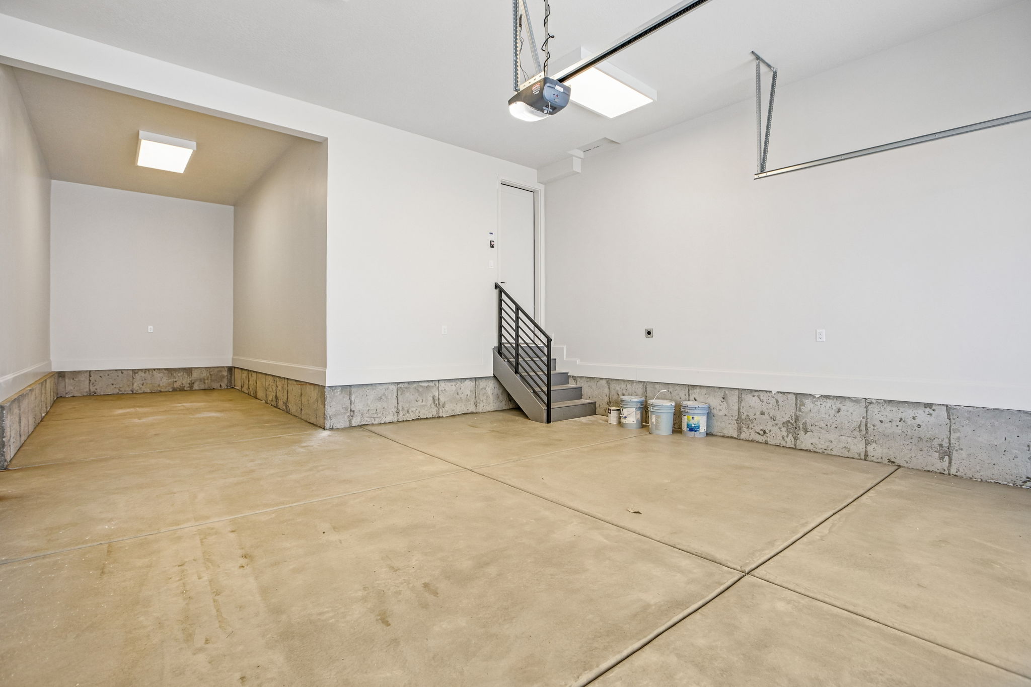 Spacious garage featuring a concrete floor, painted white walls, and a built-in storage alcove
