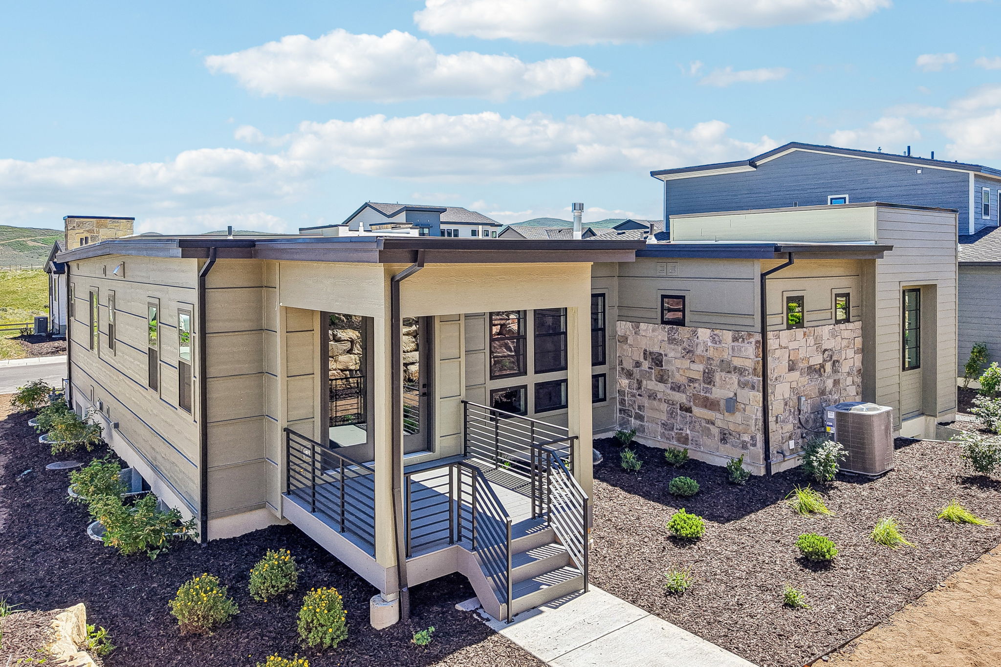 Contemporary property exterior featuring varied siding, stone accents, and a flat roofline