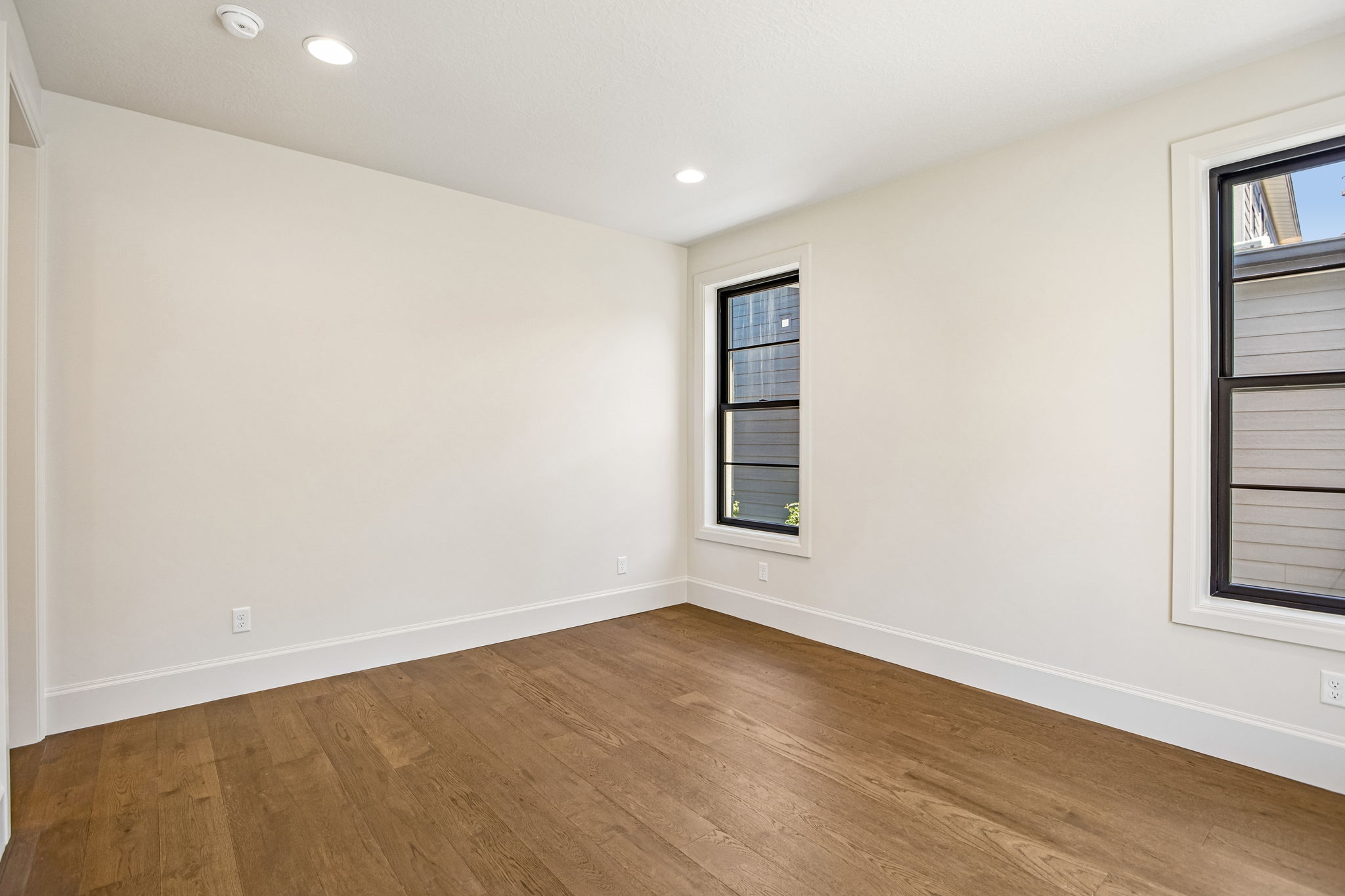 Hardwood flooring throughout, recessed ceiling lighting, and two multi-pane windows with dark frames