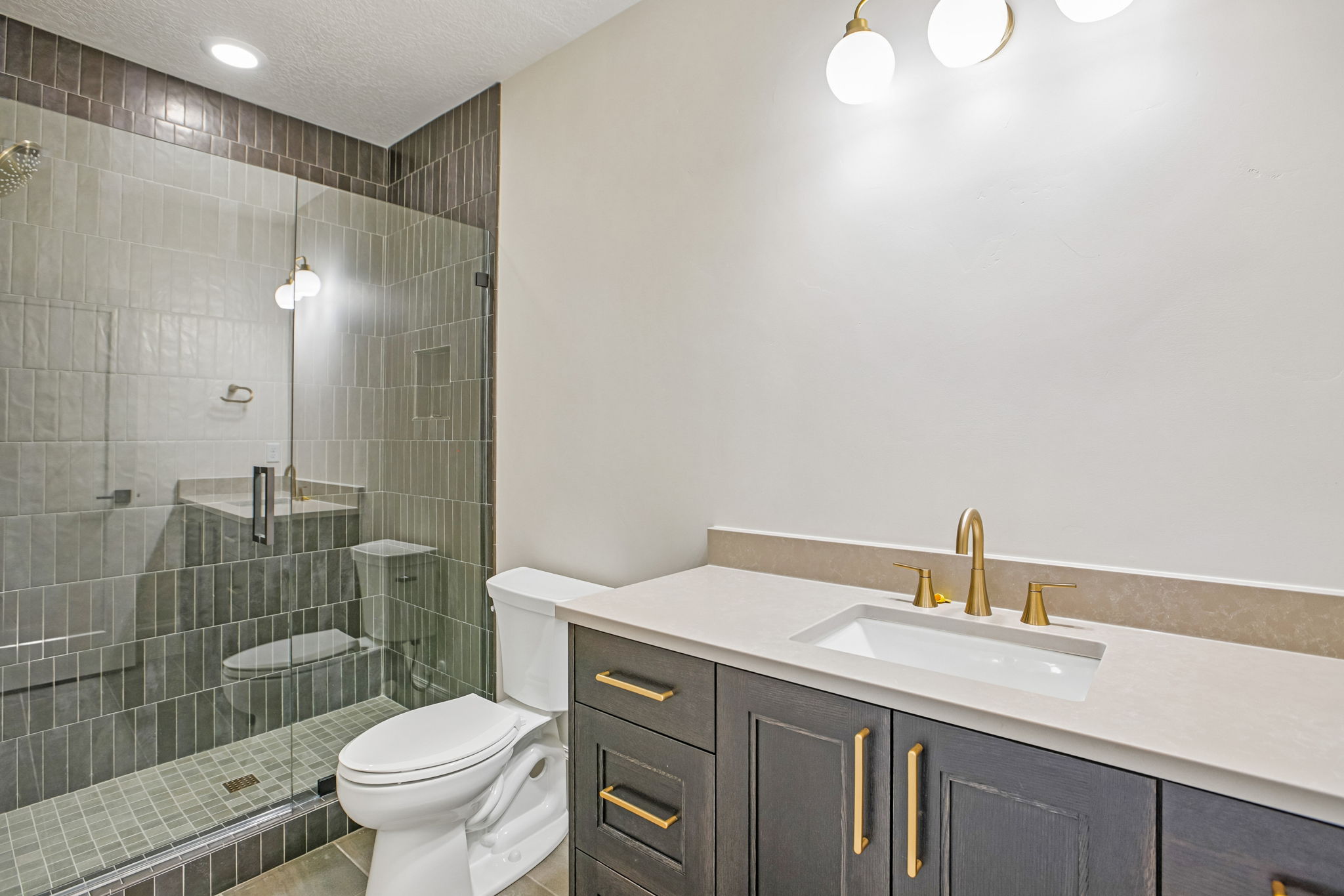 Contemporary bathroom featuring a dark wood vanity with gold-tone hardware, a light-toned countertop, and an undermount sink