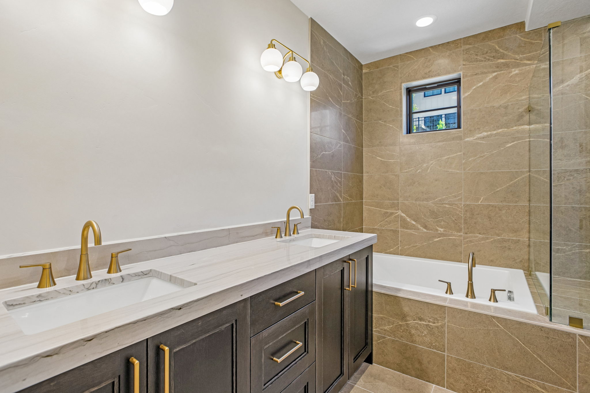 Dual vanity with white undermount sinks, gold-finish fixtures, and a light-toned countertop