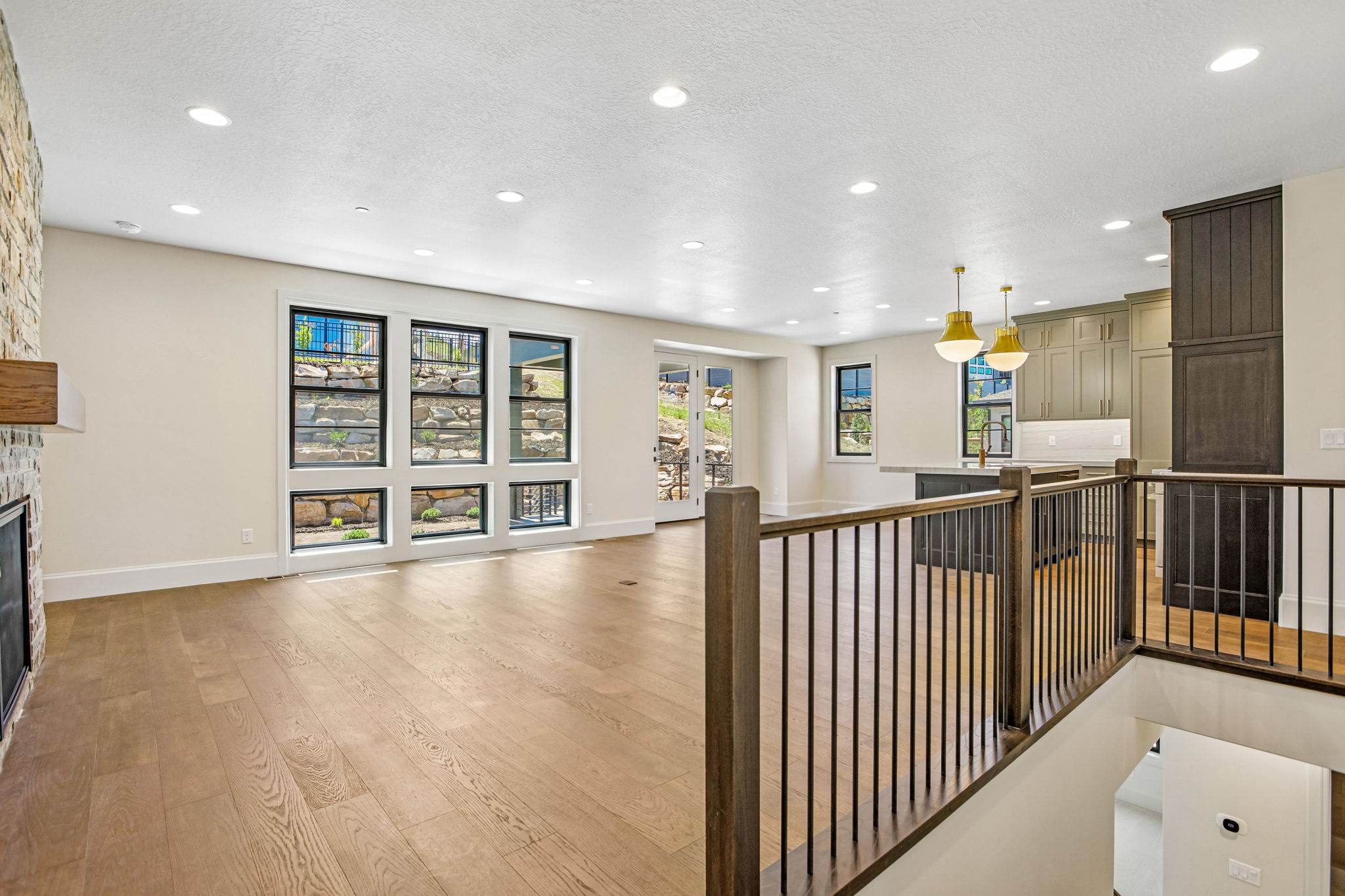 Spacious main living area featuring wide plank wood-finish flooring, recessed lighting, and a stone-clad fireplace
