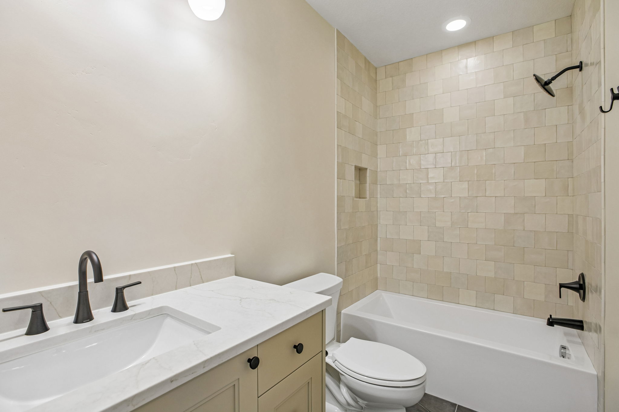 Bathroom featuring a white undermount sink, a stone-finish countertop, and a light-colored vanity with dark hardware