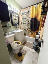 Full bathroom with vanity, shower / tub combo, and a textured wall