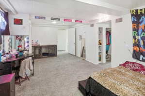 Carpeted room featuring white walls and a white ceiling with exposed beams