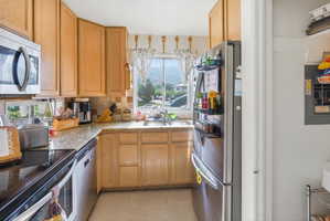 Kitchen featuring wood cabinetry, light-toned granite countertops, stainless steel appliances, and a tile backsplash