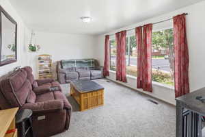 Spacious living area featuring light-colored carpeting and bright white walls