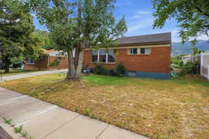 Brick exterior residence featuring a dark shingle roof, multiple windows, and a partially fenced yard