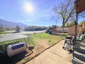 Fenced backyard featuring a mountain view, a patio, a shed, and a playground