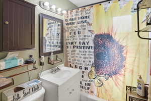 Bathroom vanity with integrated sink, mounted mirror, and overhead four-bulb light fixture