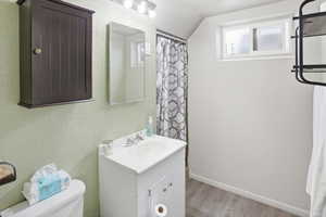 Bathroom featuring a white vanity with integrated sink, wood-finish flooring, and a sliding window