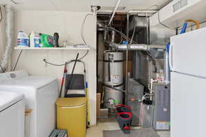 Laundry area featuring a washer and dryer, wall-mounted shelving, exposed ductwork, and a water heater