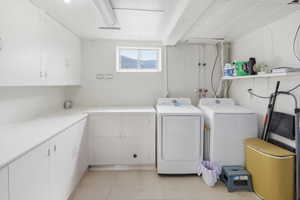 Utility space featuring extensive white cabinetry, ample counter space, a window with mountain scenery, and overhead lighting