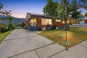 Brick exterior home with a partial concrete driveway and front yard