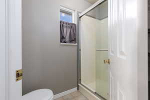 Full bath featuring a shower stall and light tile patterned floors
