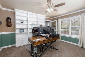 Office area with crown molding, dark colored carpet, and ceiling fan