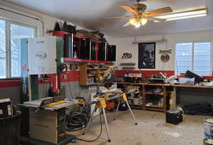 Miscellaneous room featuring ceiling fan, unfinished concrete floors, and a workshop area