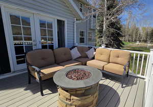 Wooden terrace featuring an outdoor living space with a fire pit and french doors
