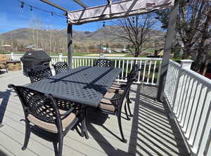 Wooden terrace featuring grilling area, a mountain view, and outdoor dining area