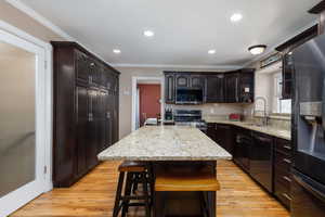 Kitchen with light stone countertops, stainless steel appliances, a kitchen breakfast bar, a center island, and open shelves