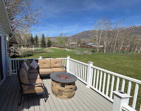Deck with a mountain view, an outdoor living space with a fire pit, and a yard